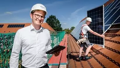 Vonovia Mitarbeiter steht auf dem Dach mit PV Installateur von Solarwatt