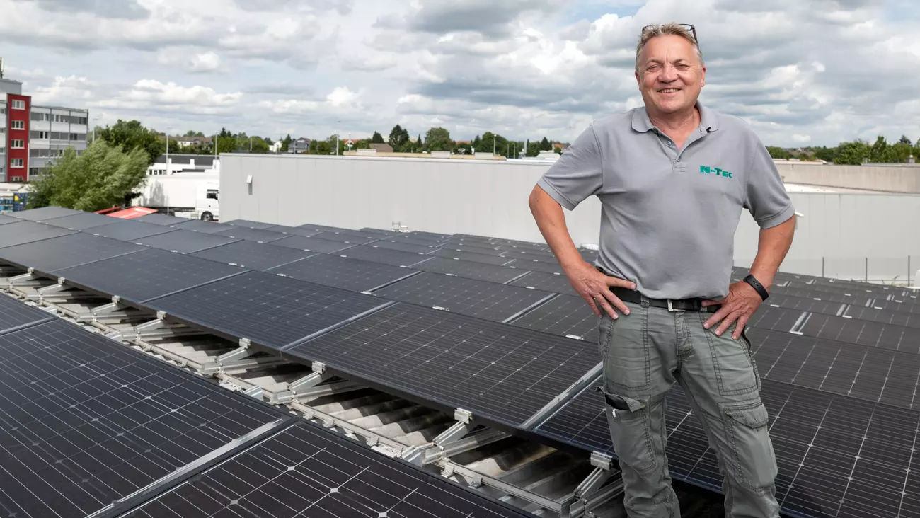 Mann steht auf einem Dach mit Solarmodulen
