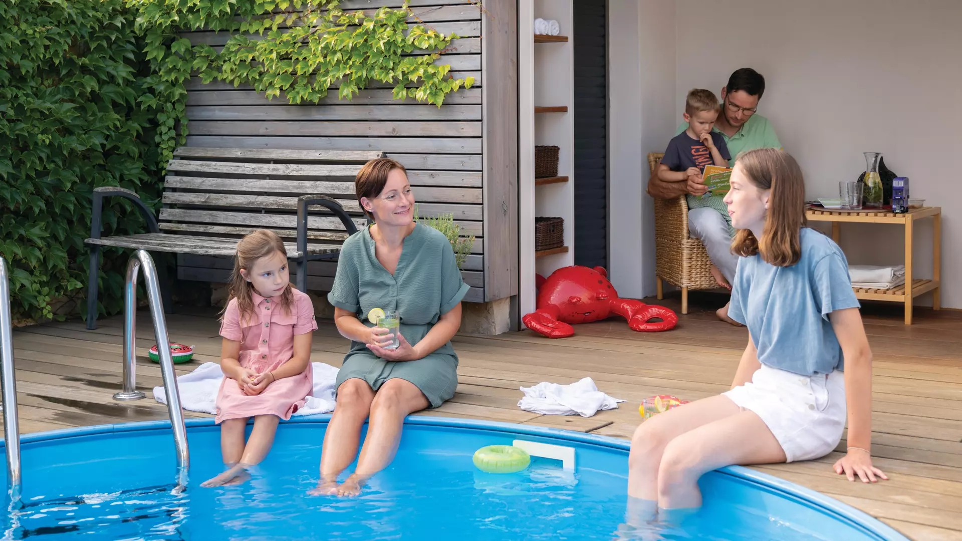 Familie erfrischt sich am eigenen Pool im Garten